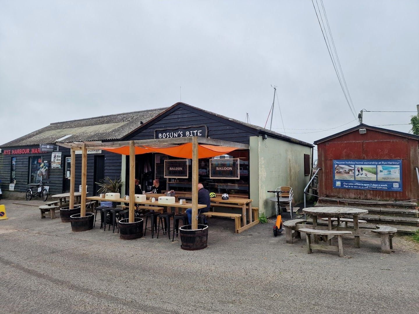 Bosun’s Bite from the car park: the black timber café, orange shade sails over the outdoor tables and wooden picnic benches